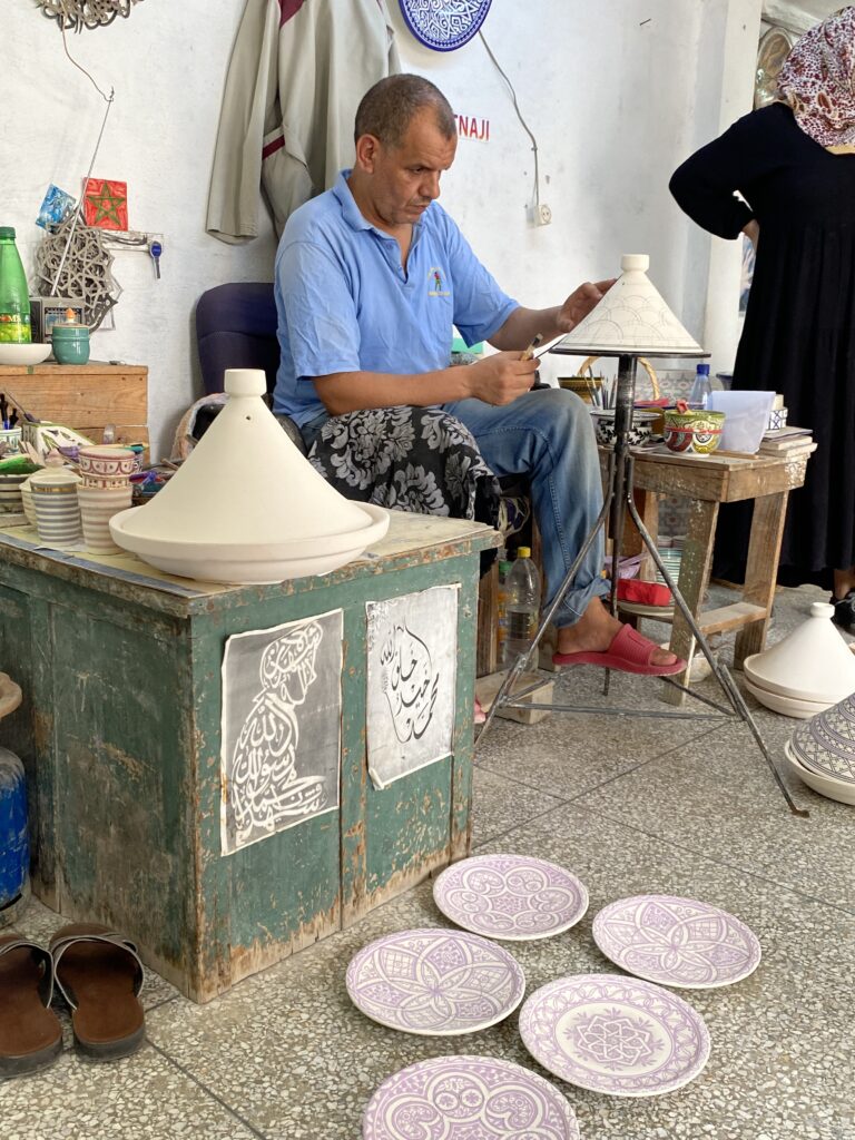 Man decorating a Moroccan tagine in a Fez pottery studio