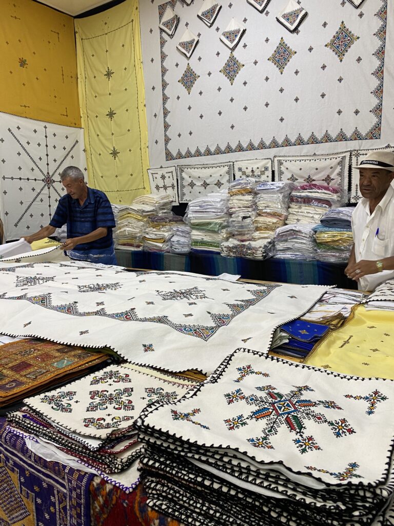 Two men showing display of traditional Berber stitched textiles