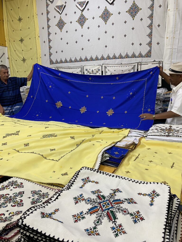 Two men showing display of traditional Berber stitched textiles