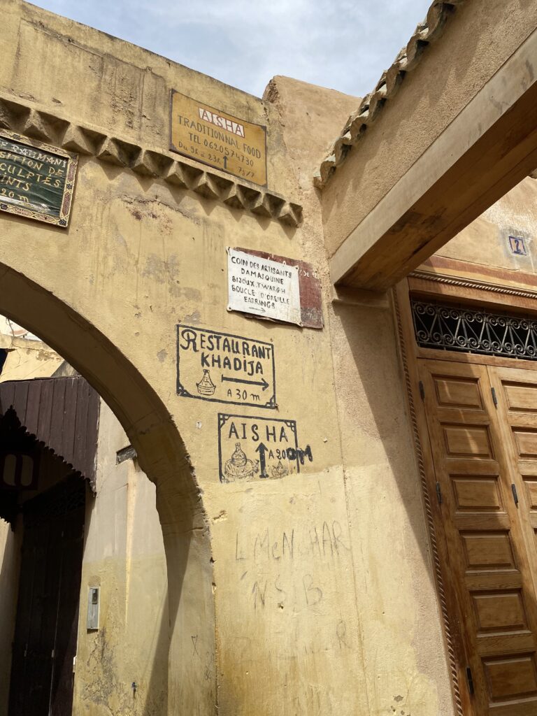 Signs to a restaurant painted on stone medina walls in Meknes Morocco