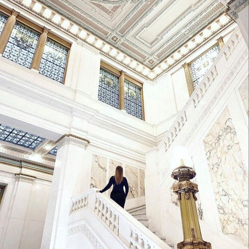 Woman walking up white marble staircase in upscale hotel lobby