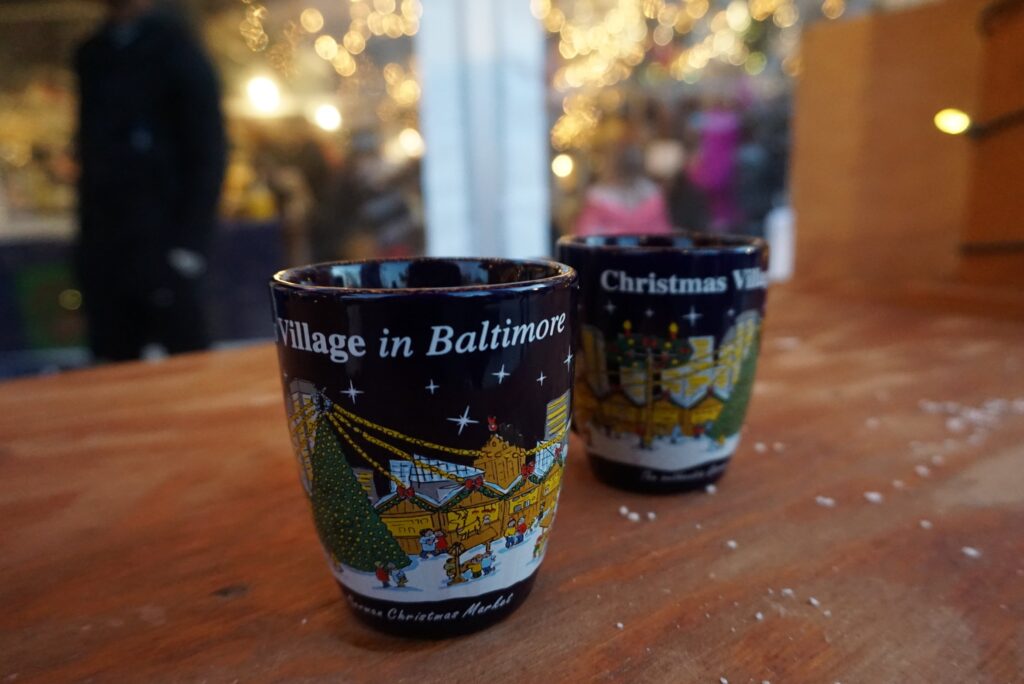 Two Christmas in Baltimore mugs on a wooden outdoor holiday market table