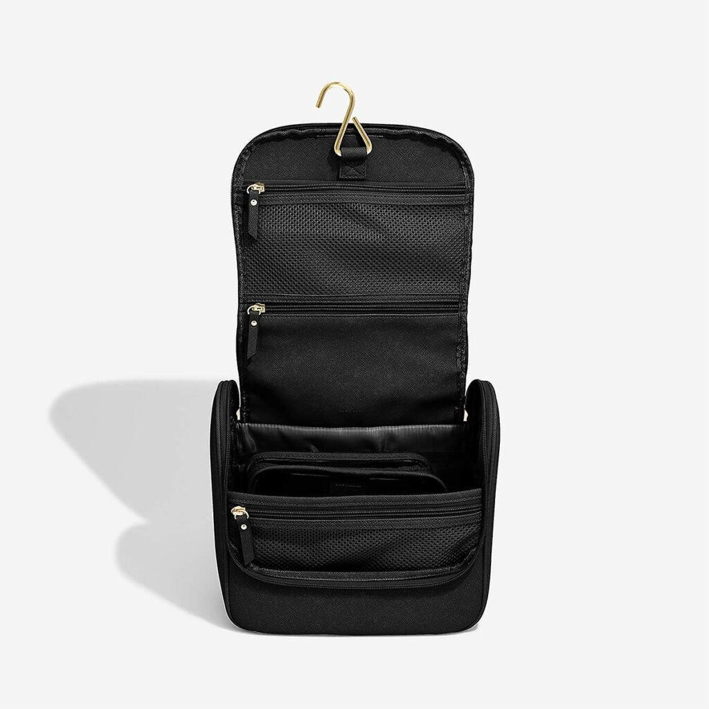 An open black toiletry bag with a gold hanging hook at the top