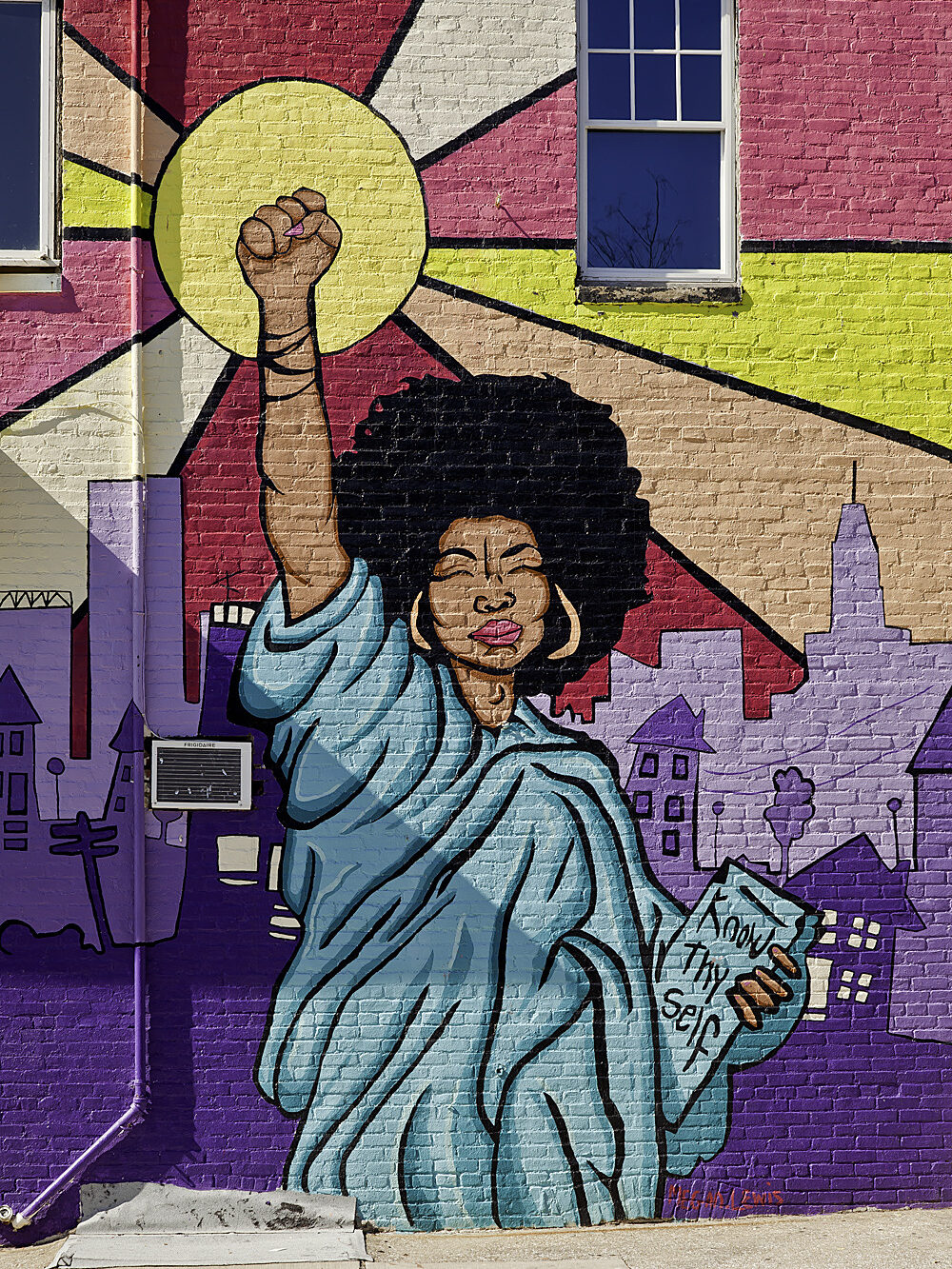 Colorful street mural of woman with afro dressed as statue of liberty