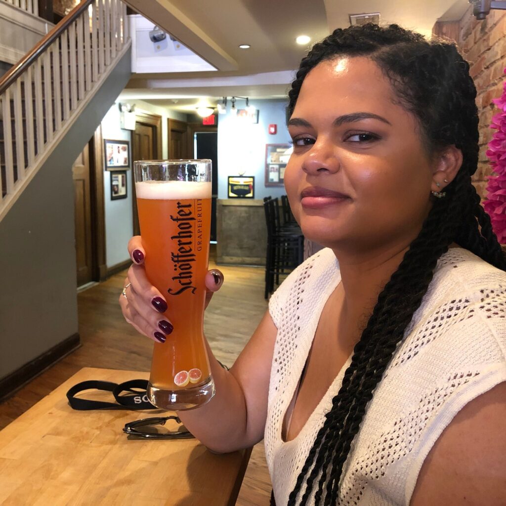 Woman at a bar table holding a mug of beer