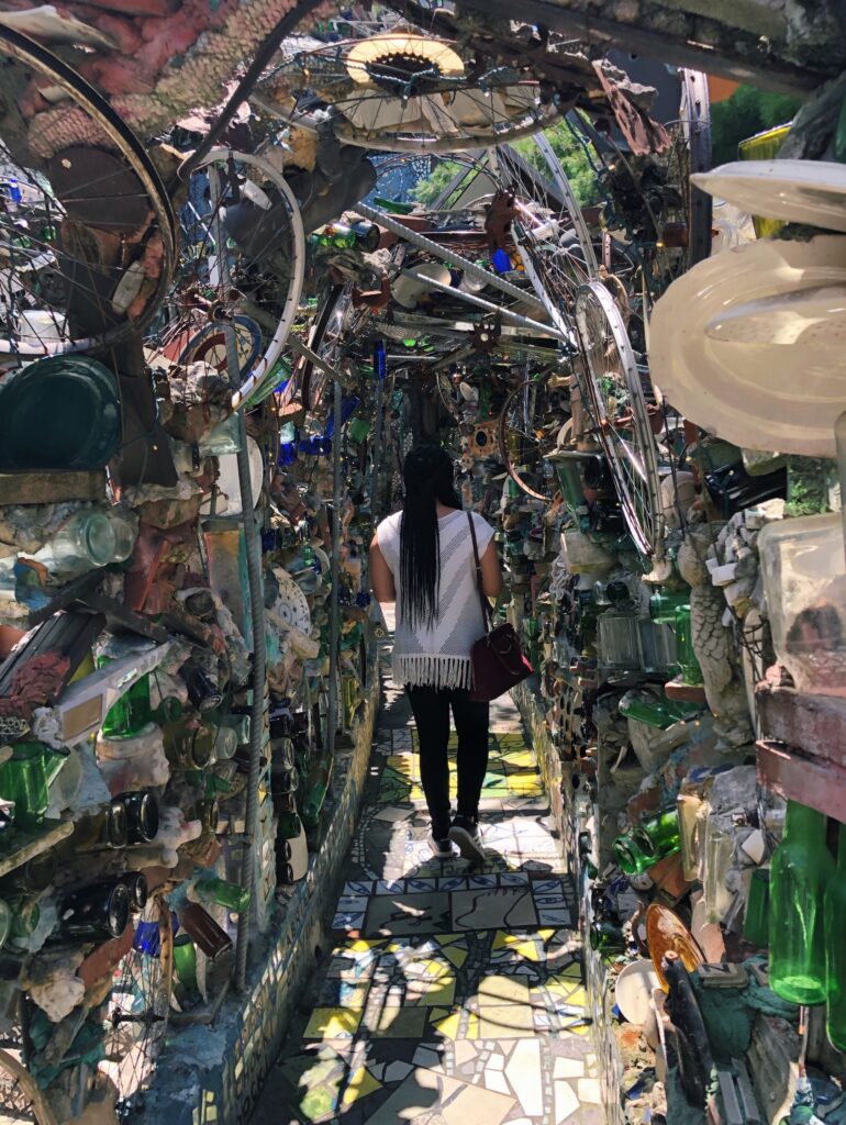 Woman walking through an art installment of glass bottles, ceramic, and found items