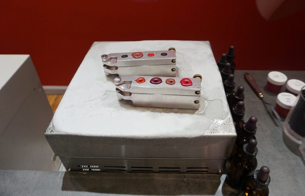 Two lipstick molds being chilled on a cold metal block