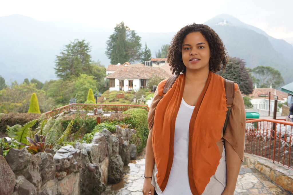 Woman in front of a Spanish-stye building and greenery on top of a mountain in Colombia.