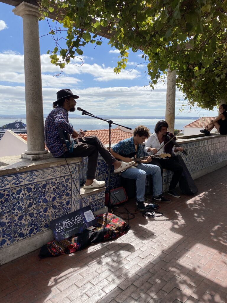 Three musicians performing on a viewpoint balcony in Lisbon Portugal