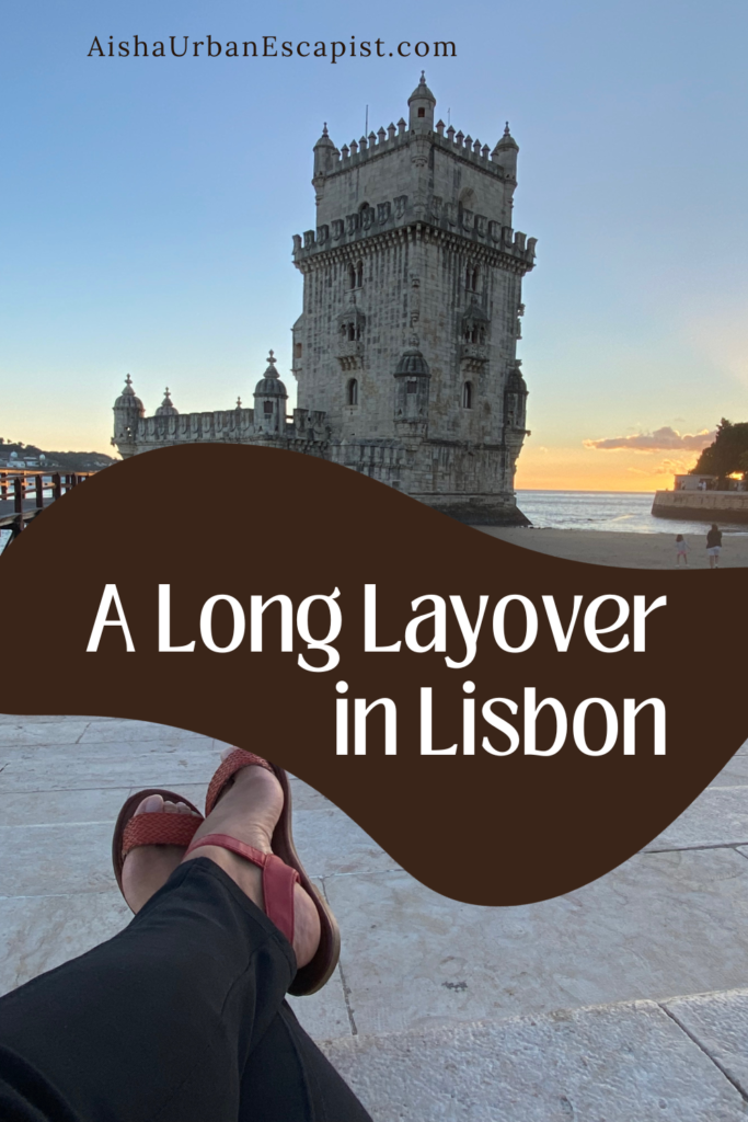 Tower on the beach with woman's feet crossed sitting in front of it with the title "A long layover in Lisbon"