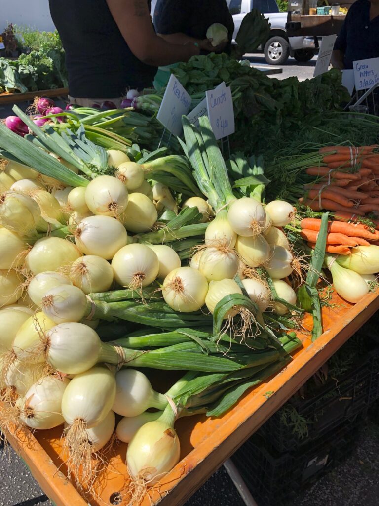 Onions and carrots on a outdoor farmers market table
