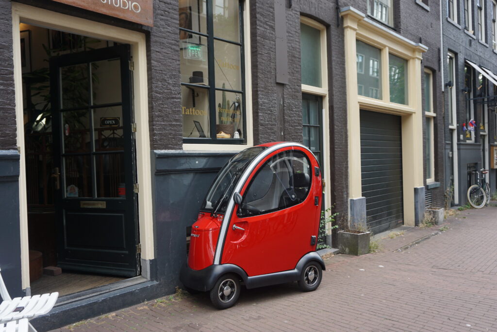 Tiny red car parked on a sidewalk in Amsterdam Netherlands