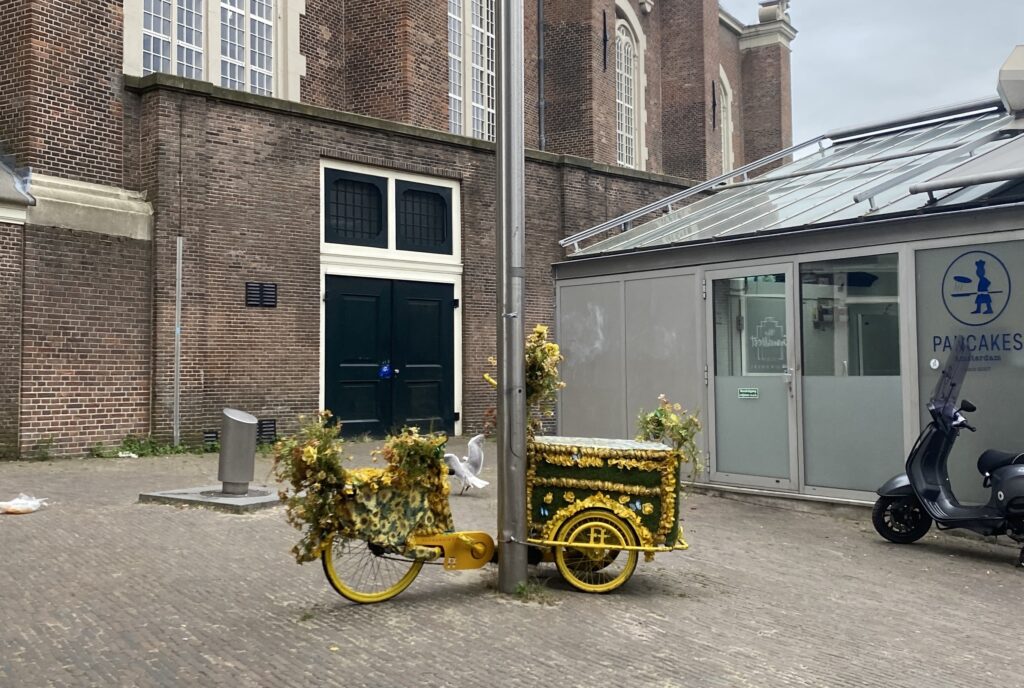 Bike with an attached carriage decorated with yellow flowers on an Amsterdam street