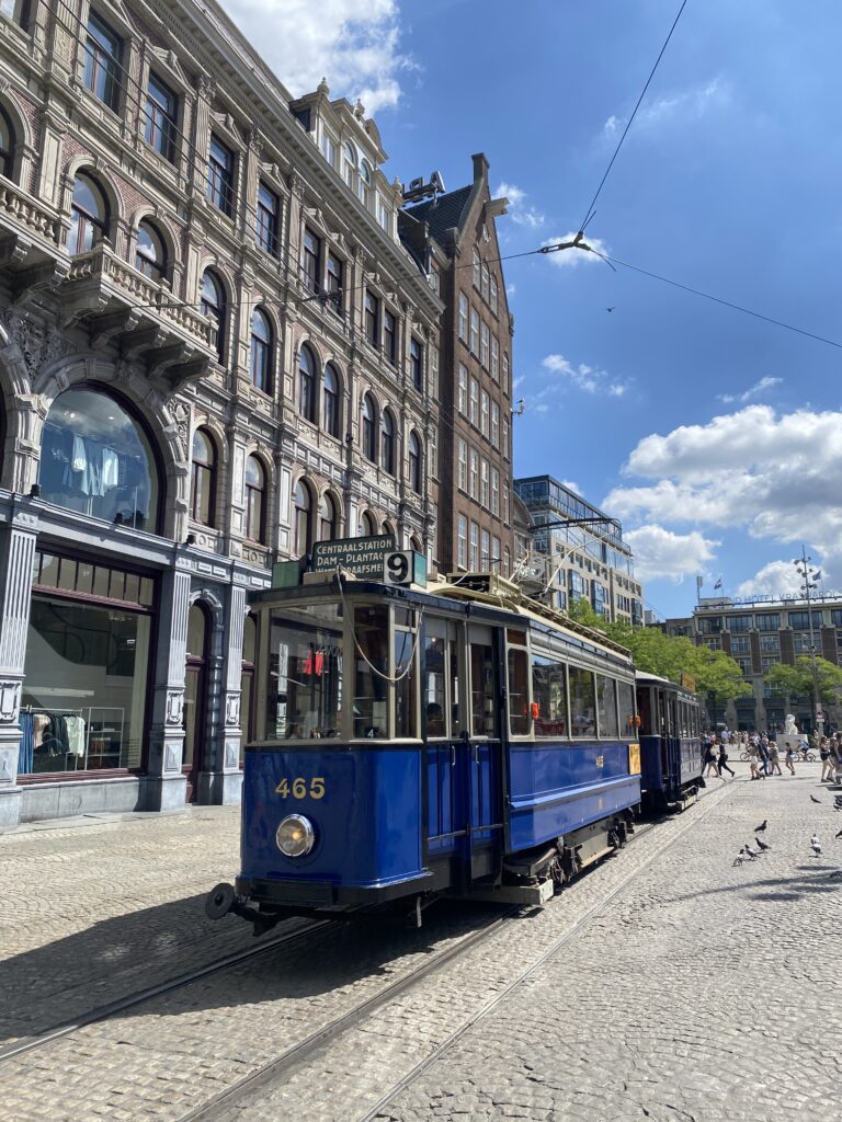 Blue trolley stopped in a plaza in the center of Amsterdam Netherlands