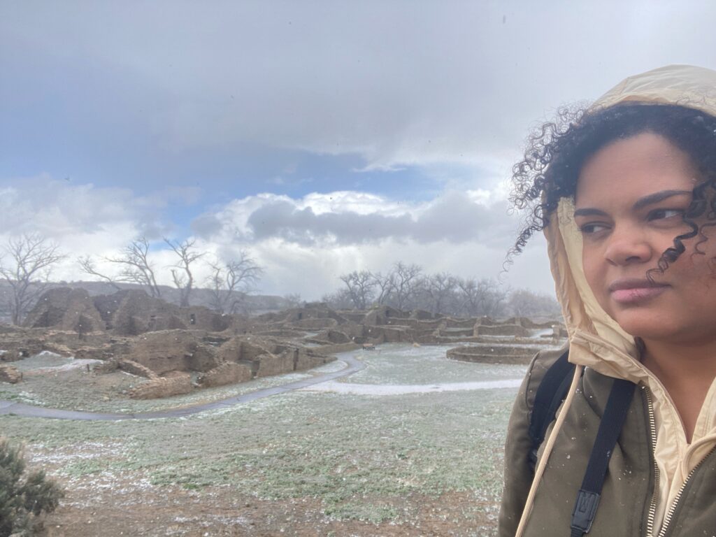 Woman in jacket with Aztec ruins in background as it snows