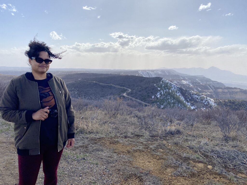 Woman in foreground with a large mesa and valley in the background