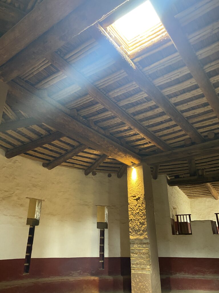 Inside of an underground kiva with light shining down from the square opening