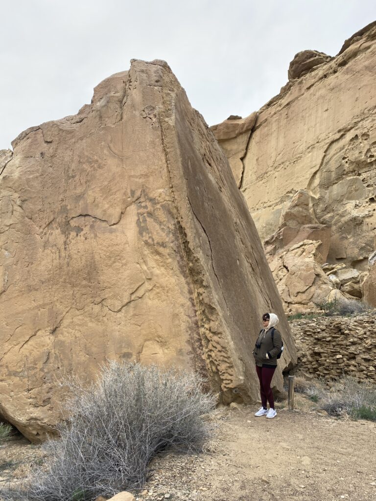 Woman standing next to a large rock that towers above her in New Mexico