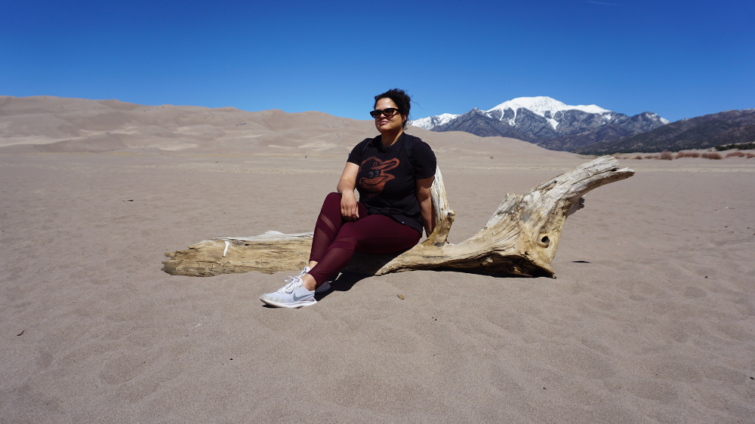 Woman sitting on log amid sand dunes during new mexico and southern colorado trip