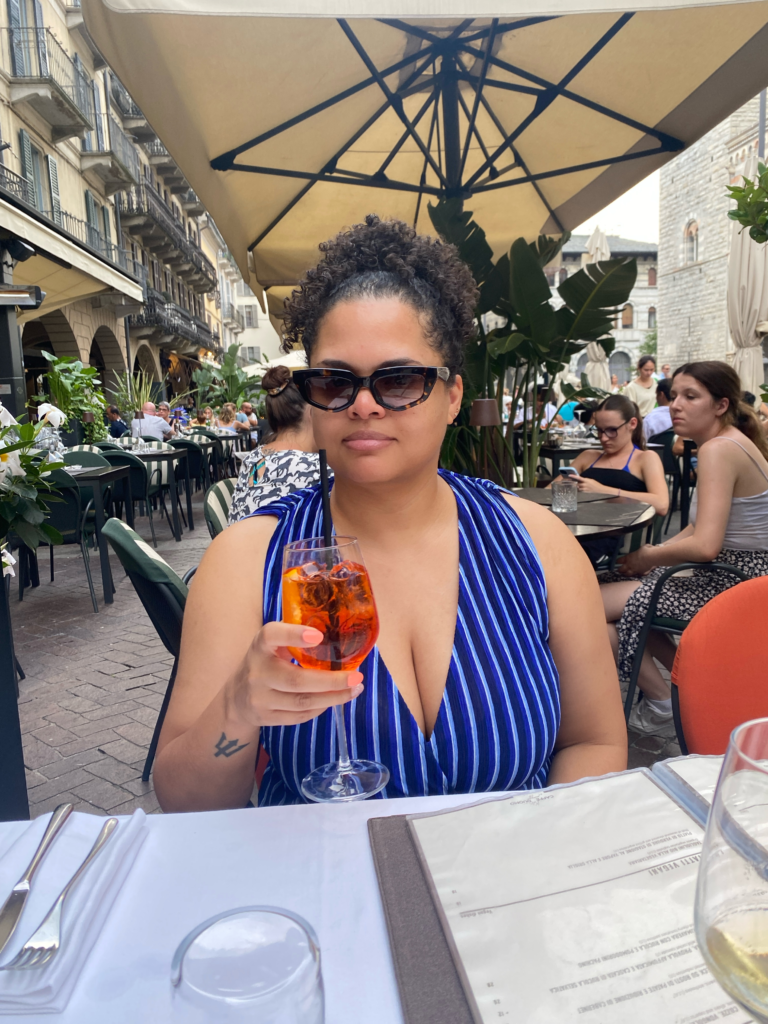 Woman sitting at outdoor restaurant holding a glass of Aperol Spritz