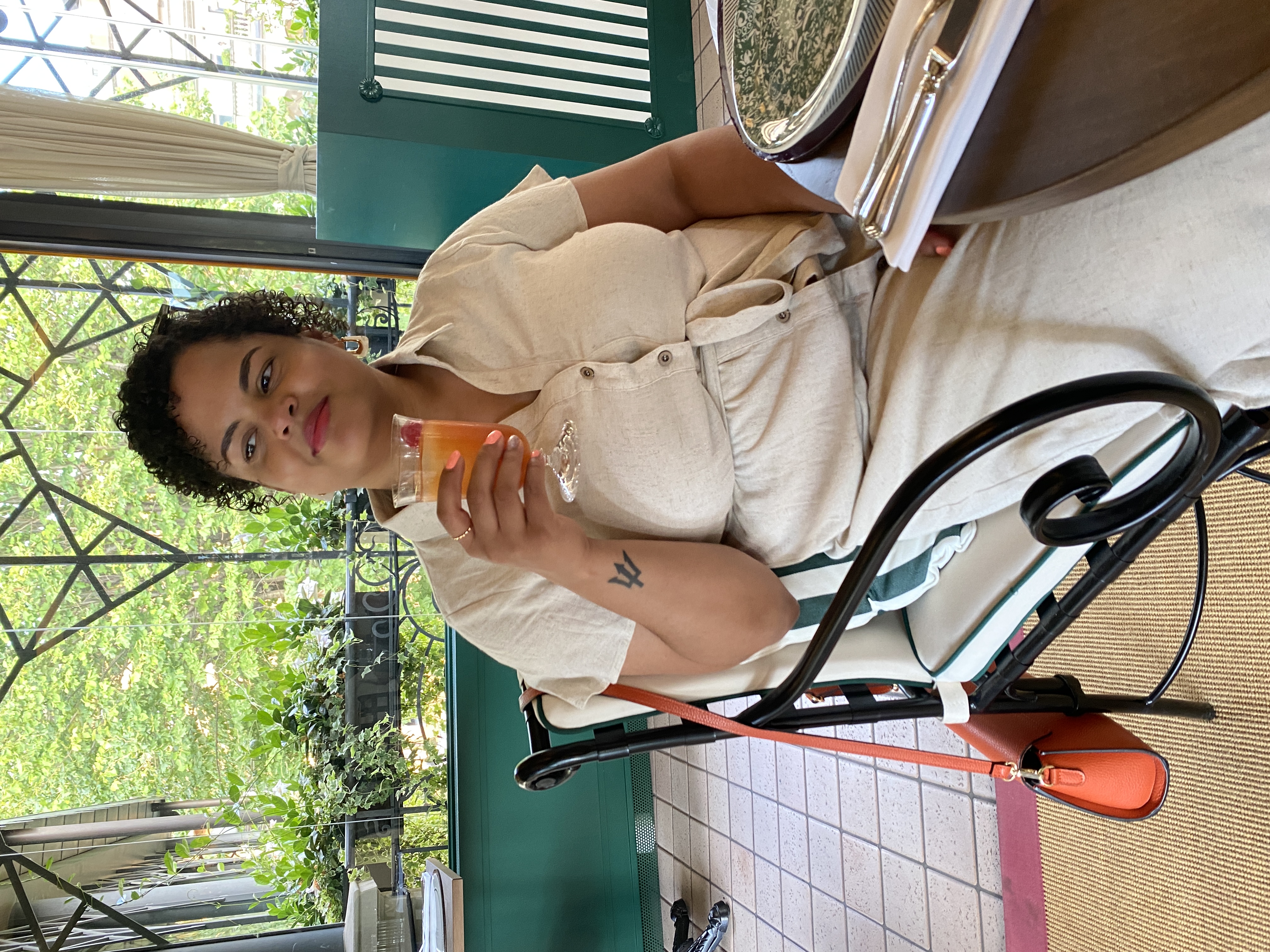 Woman sitting at a restaurant table holding a cocktail