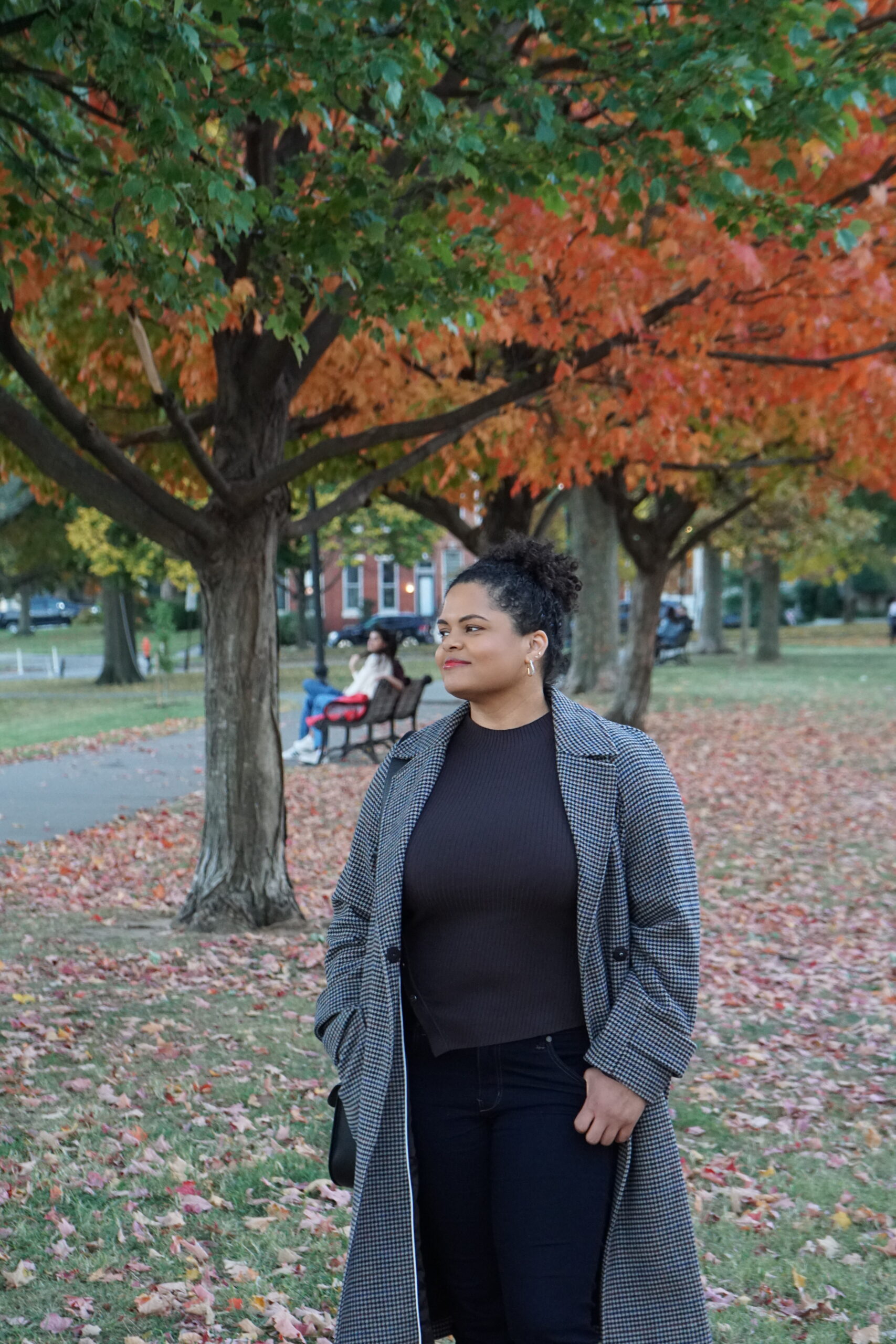 Woman in park with autumn trees and orange leaves in the background