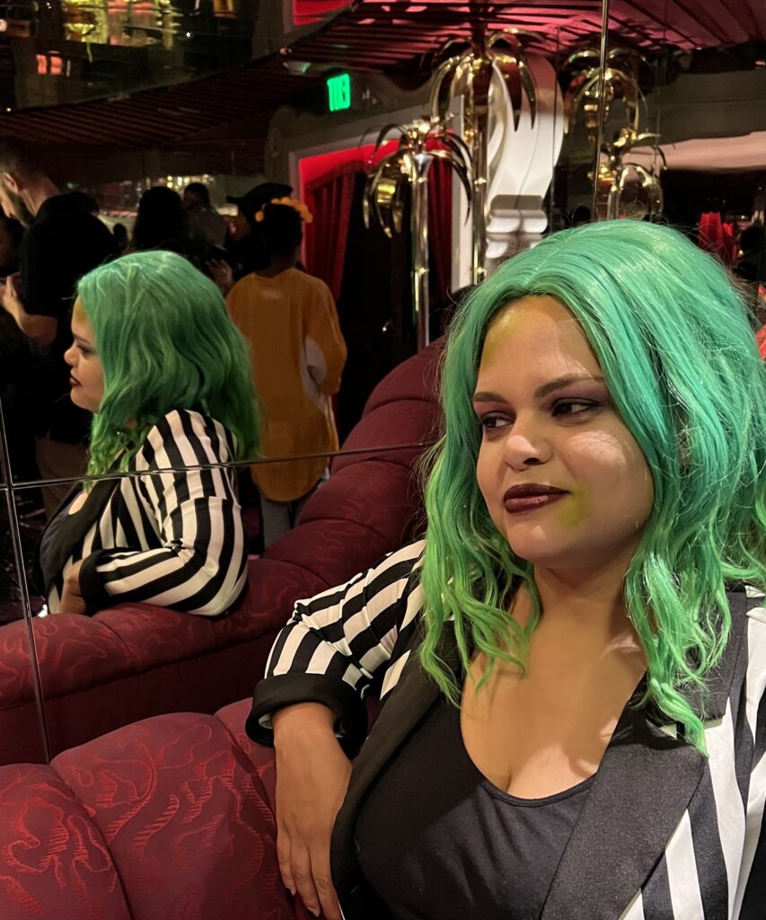 Woman in Beetlejuice Halloween costume of green wig and black and white striped suit