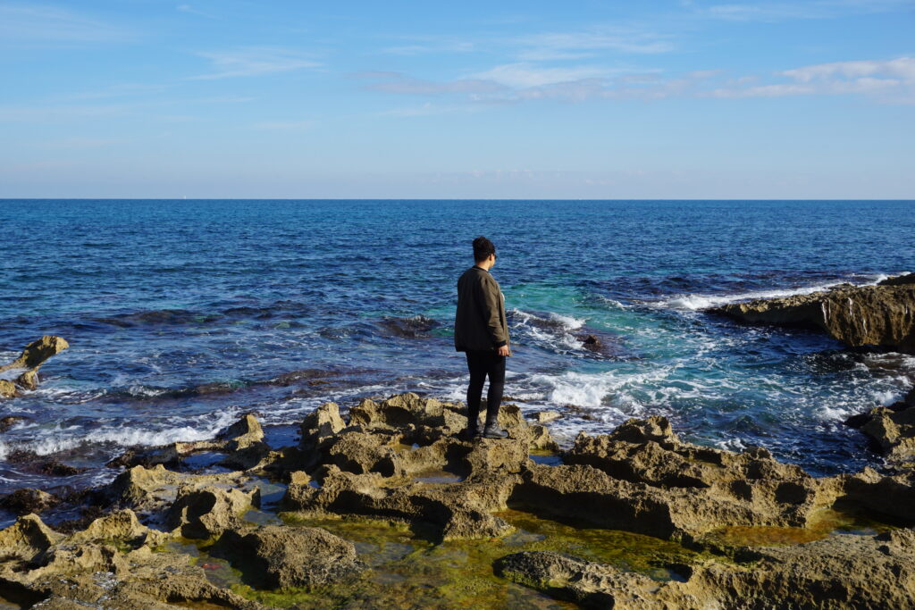 Woman standing on rocky shore of a Spanish Mediterranean town called Javea