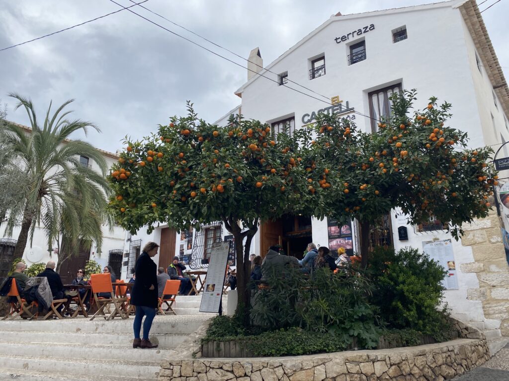 Orange trees beside a restaurant with outdoor seating in the historic town center of Altea, Spain
