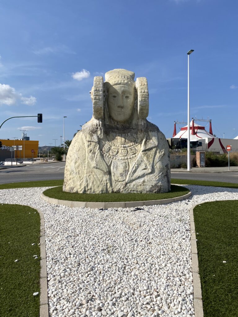 A large, white sculpture in the center of a street roundabout