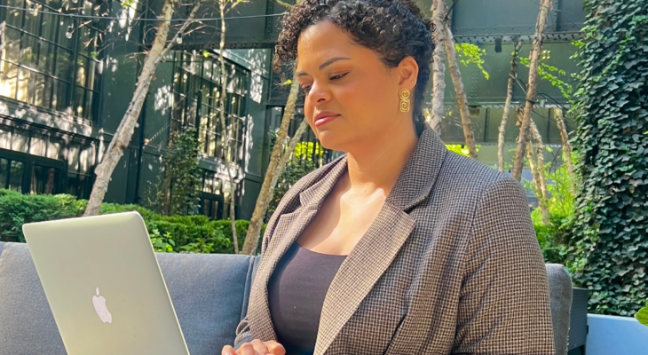 Woman working on a laptop with greenery in the background