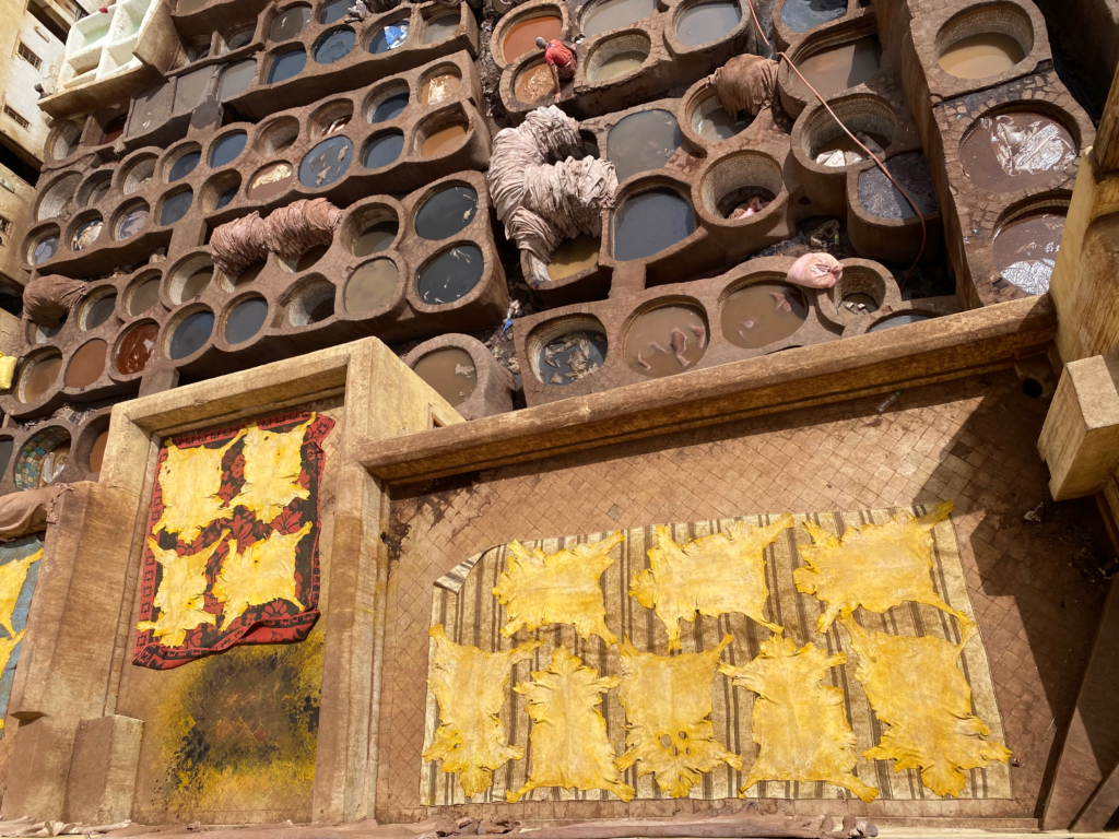 Honeycomb stone vats with workers dying animal skins and skins laying out to dry under the sun in Fes Morocco