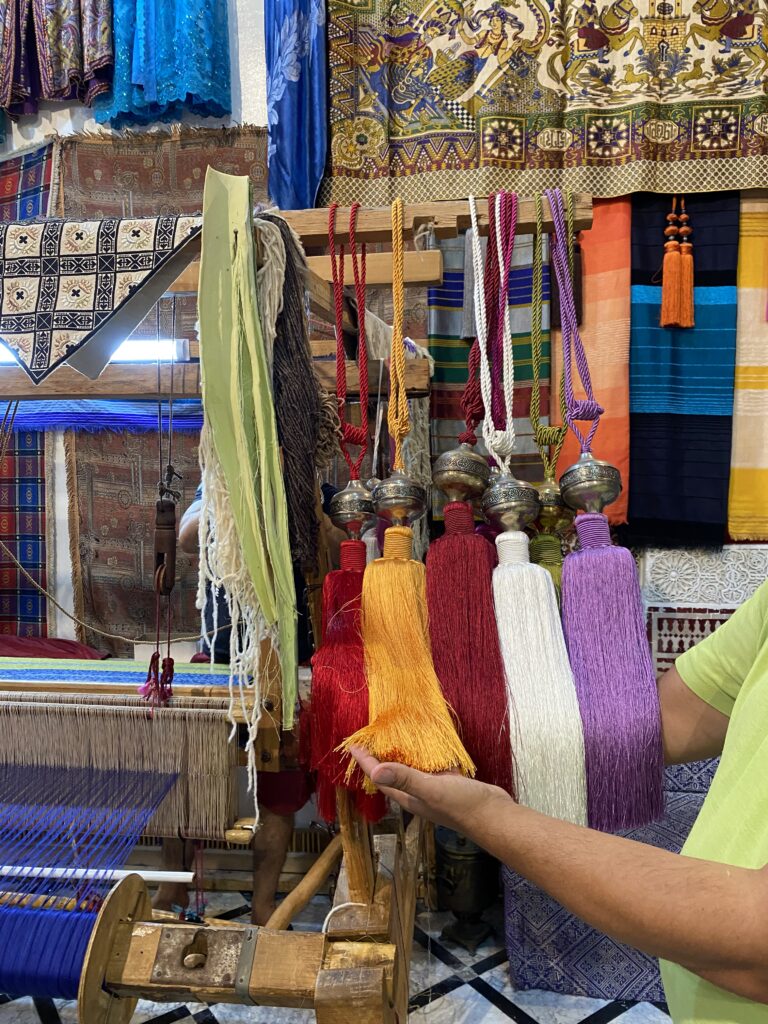 Man showing three sabra silk tassels in Morocco medina
