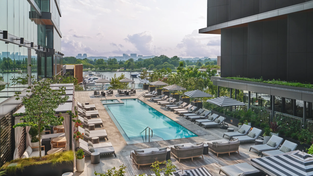 View of hotel outdoor patio with pool and lounge chairs and the Potomac River and city skyline beyond it