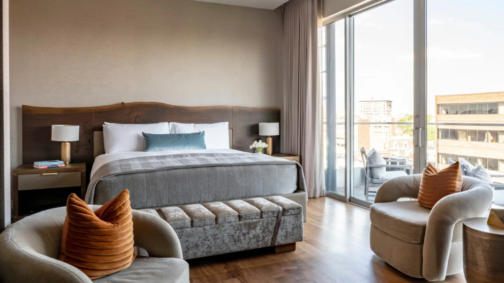 Penthouse Suite at the Dupont Circle hotel with bed, two armchairs, and floor to ceiling windows looking out on the city