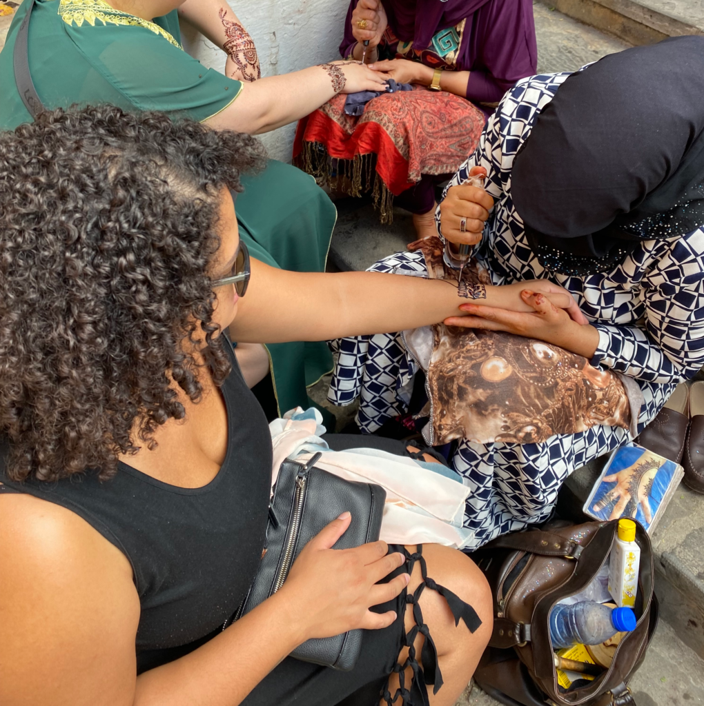Moroccan woman applying henna to woman in black dress