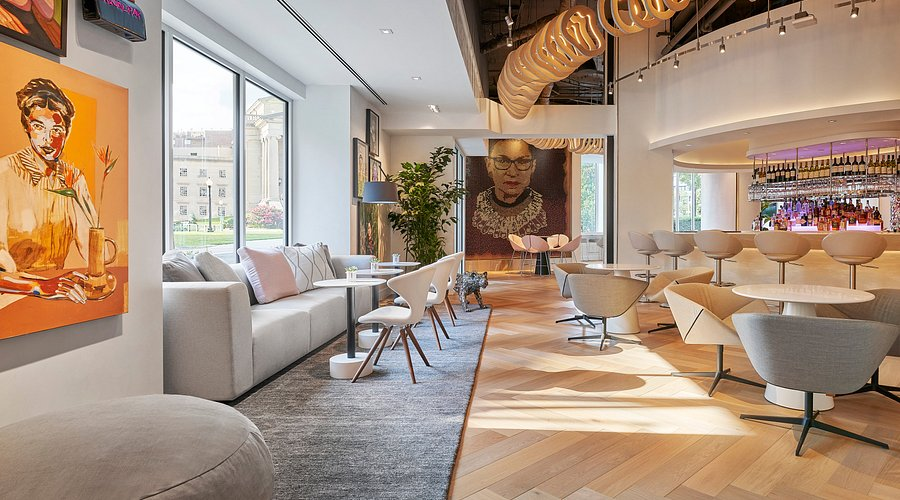 Hotel bar area with artwork on the walls and bright sunlight coming through large windows