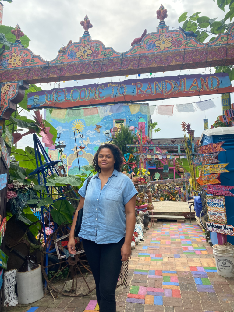 Woman standing in front of colorful entrance to outdoor garden