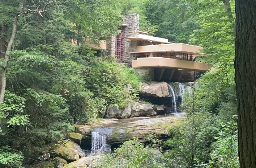 View through the woods of an architectural house and two waterfalls beneath it